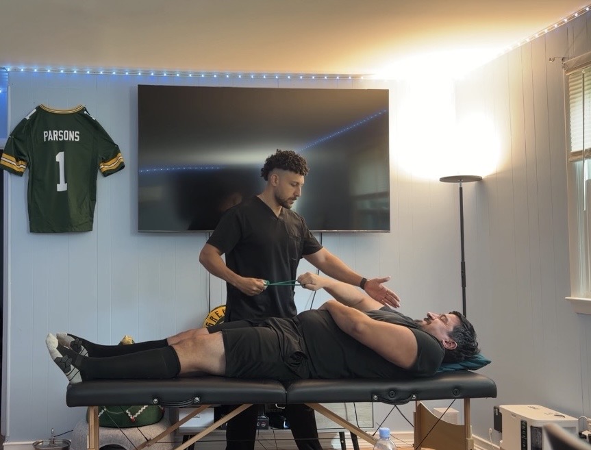 Dr. Baskaron performing in-home physical therapy — patient lying on portable treatment table during a session in Northern Virginia